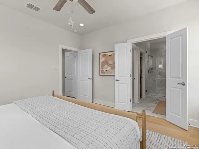 a bedroom with a large bed and a chandelier fan