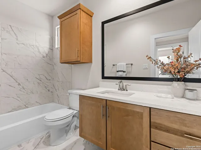 a bathroom with a granite countertop sink a toilet and mirror