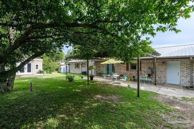 a view of a backyard with table and chairs and a large tree