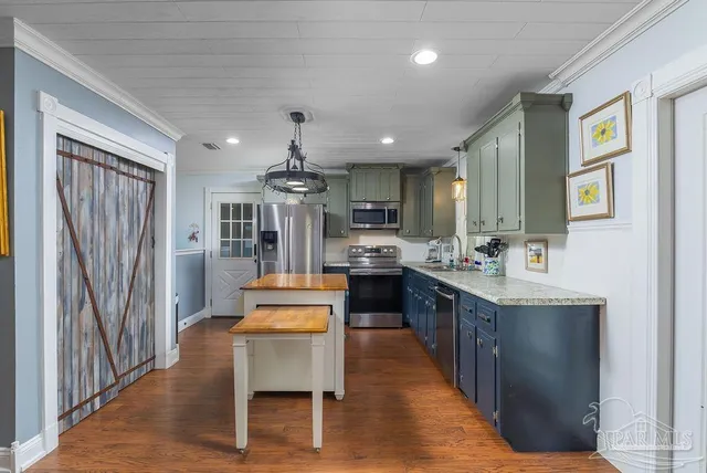 a large kitchen with stainless steel appliances kitchen island granite countertop a table chairs in it and a wooden floors