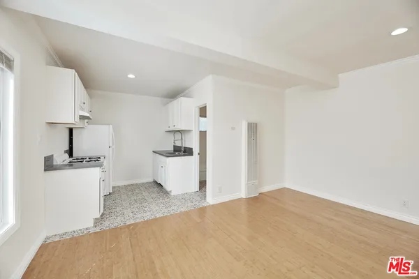 a living room with stainless steel appliances kitchen island a sink cabinets and wooden floor