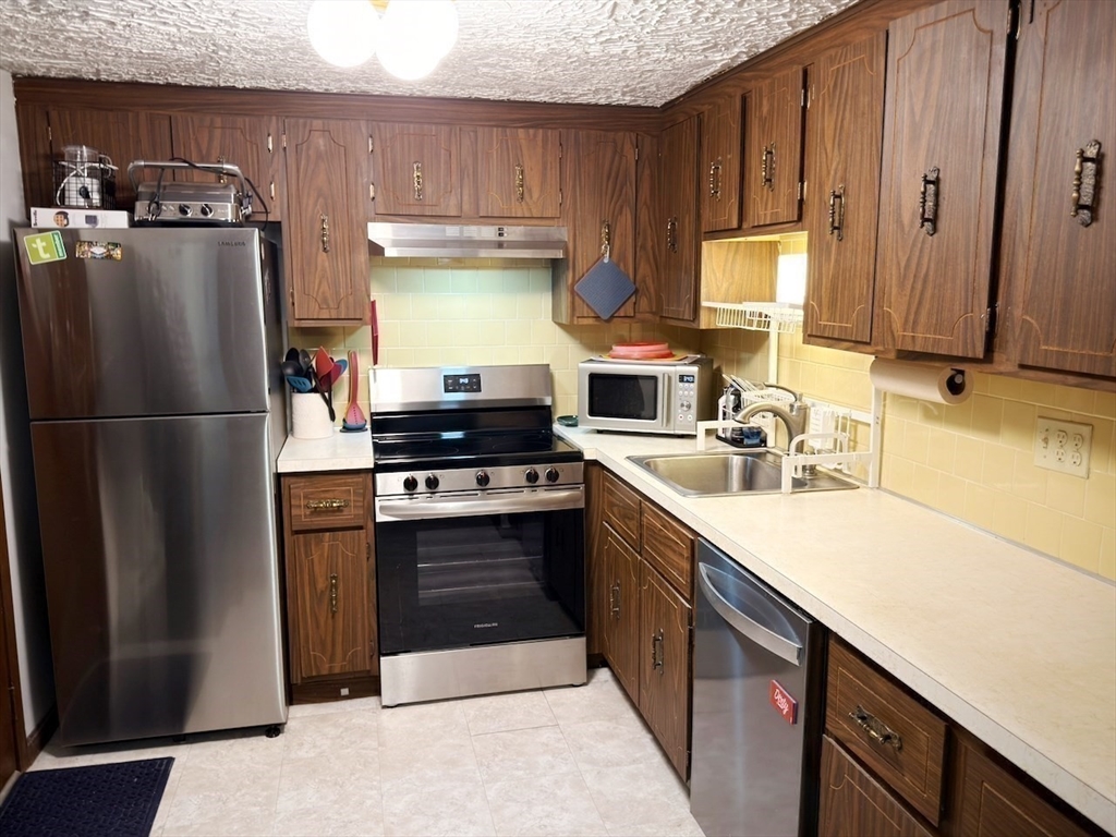 42 Swanson Court, Unit 14A Boxborough, MA 01719 - Photo 3 of 11 a kitchen with stainless steel appliances granite countertop a refrigerator stove and sink