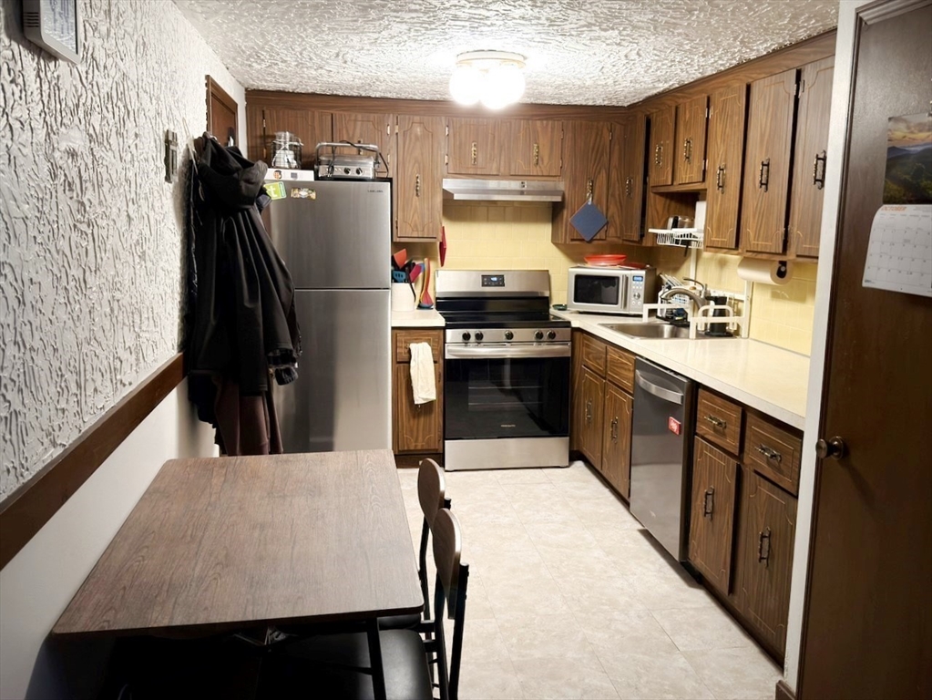 42 Swanson Court, Unit 14A Boxborough, MA 01719 - Photo 4 of 11 a kitchen with stainless steel appliances a refrigerator sink stove microwave and cabinets