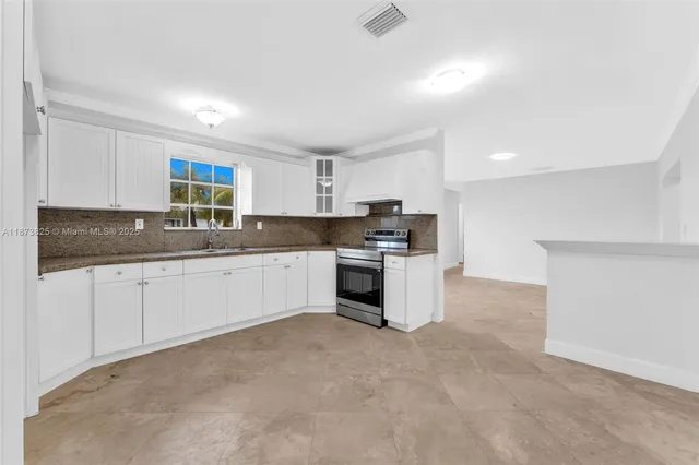 a kitchen with granite countertop white cabinets and stainless steel appliances