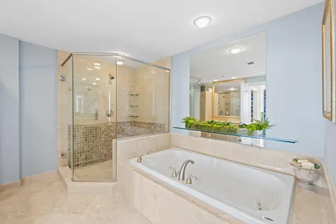 a bathroom with a tub a sink and a large mirror