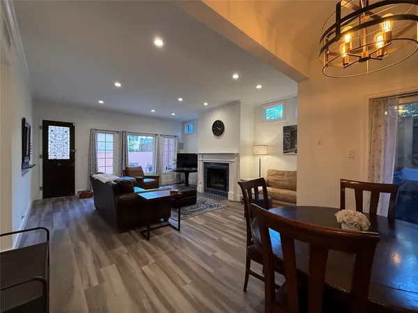 a living room with furniture a fireplace and a dining table with wooden floor
