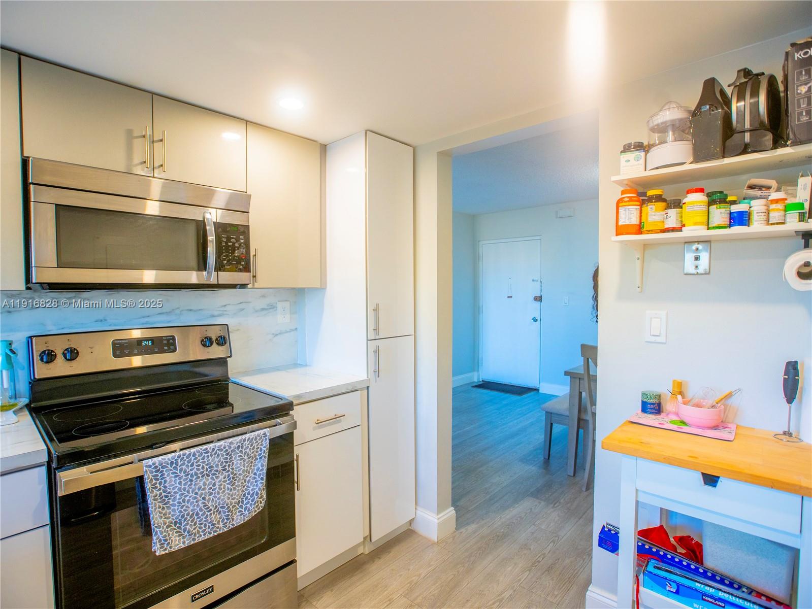 9400 West Flagler Street, Unit 313 Miami, FL 33174 - Photo 13 of 35 a kitchen with stainless steel appliances a stove a microwave and wood cabinets