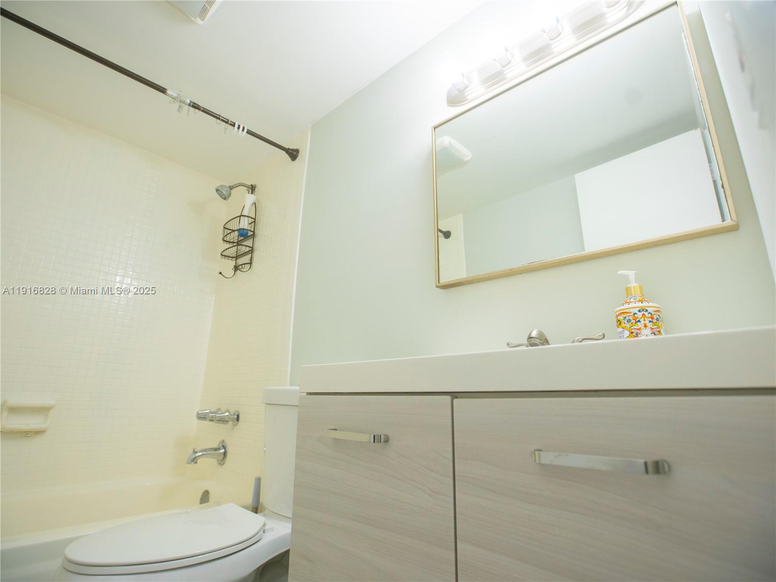 9400 West Flagler Street, Unit 313 Miami, FL 33174 - Photo 25 of 35 a bathroom with a sink a toilet and a mirror