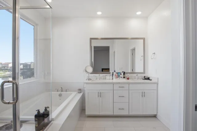 a bathroom with a double vanity sink a mirror and a bathtub