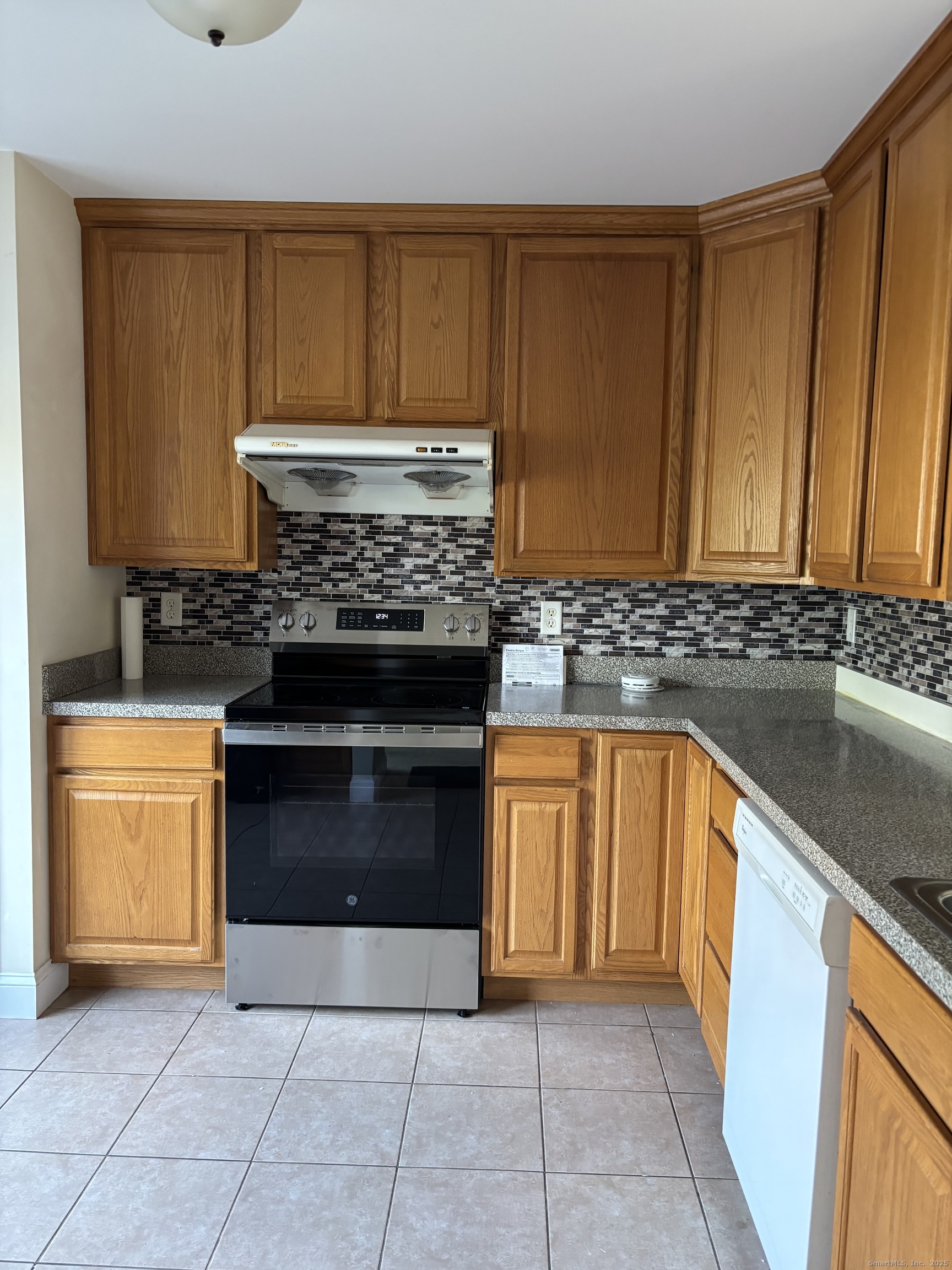 15 Freedom Way, Unit 22 East Lyme, CT 06357 - Photo 2 of 26 a kitchen with granite countertop a stove top oven cabinetry a sink and a refrigerator