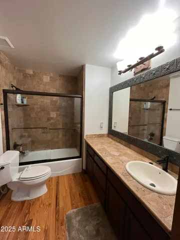 a bathroom with a granite countertop sink a toilet a mirror and shower