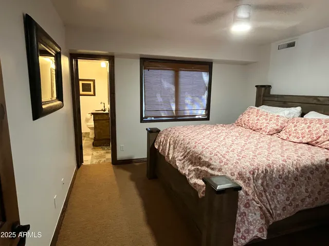 a bedroom with a bed and a large mirror next to a window