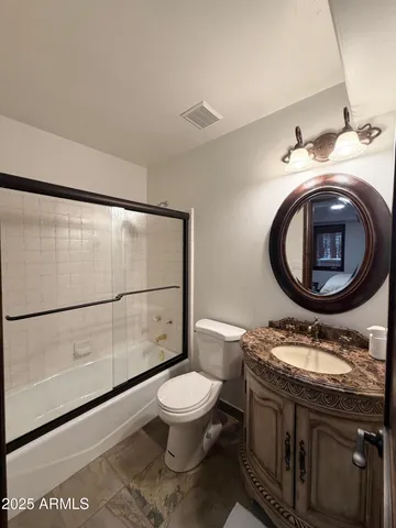 a bathroom with a granite countertop toilet sink and mirror