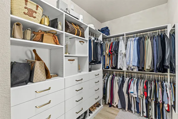 a view of walk in closet with clothes and shoes