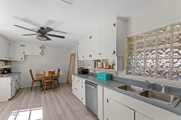 a kitchen with stainless steel appliances white cabinets a sink dishwasher and a stove with wooden floor