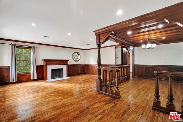 a view of an empty room with wooden floor fireplace and a window