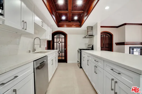 a large white kitchen with a sink and dishwasher