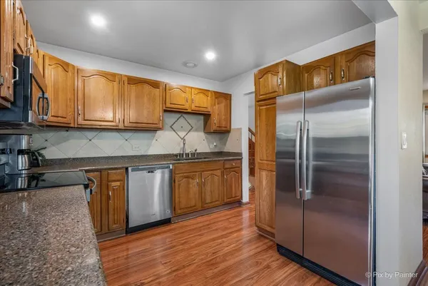 a kitchen with stainless steel appliances granite countertop a refrigerator a sink and wooden cabinets