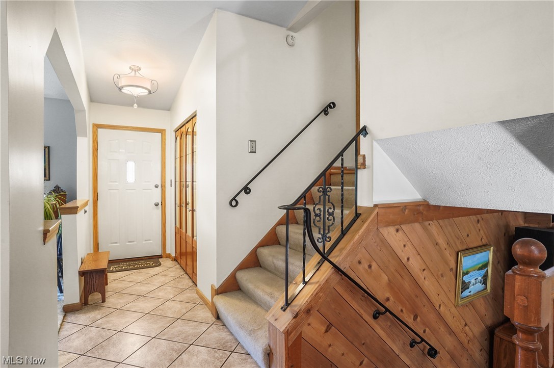 Foyer with wood walls and light tile flooring