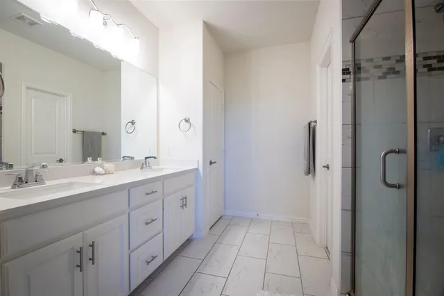 a spacious bathroom with a double vanity sink a mirror and shower