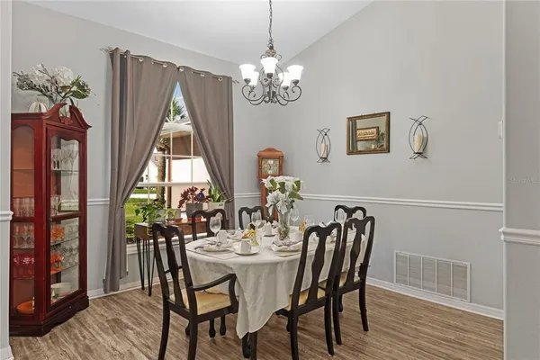 a dining room with furniture a chandelier and wooden floor