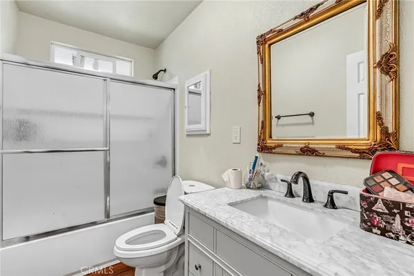 a bathroom with a granite countertop sink toilet a mirror and shower
