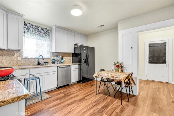 a kitchen with a table chairs a sink and dishwasher a refrigerator with wooden floor