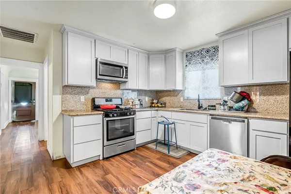 a kitchen with granite countertop a stove top oven sink and cabinets