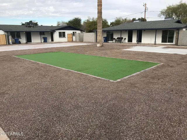 a view of house in front of big yard with large tree