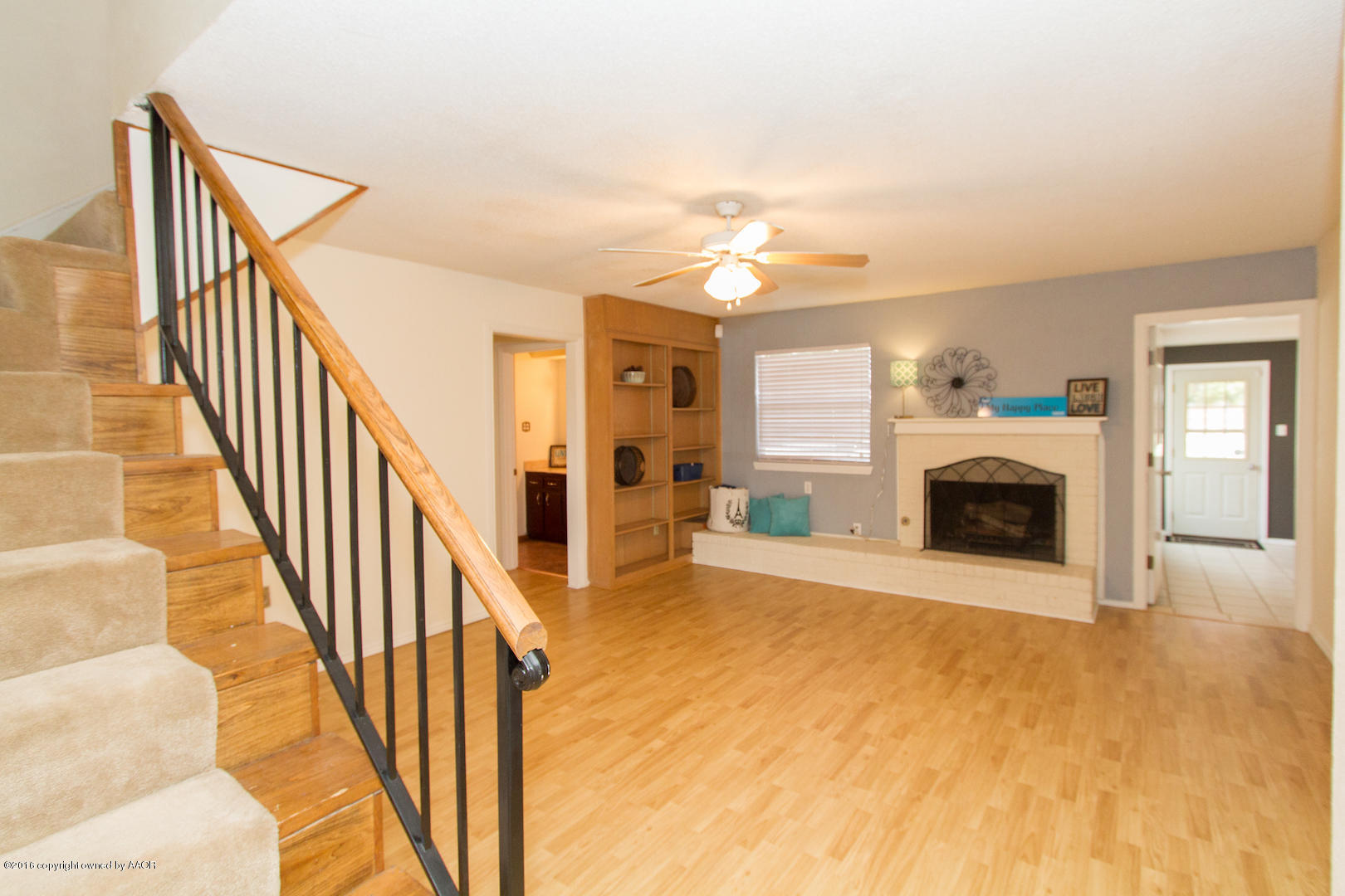 a view of a livingroom with a fireplace a ceiling fan and windows