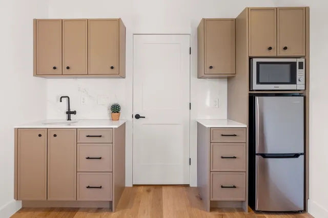 a kitchen with white cabinets and refrigerator