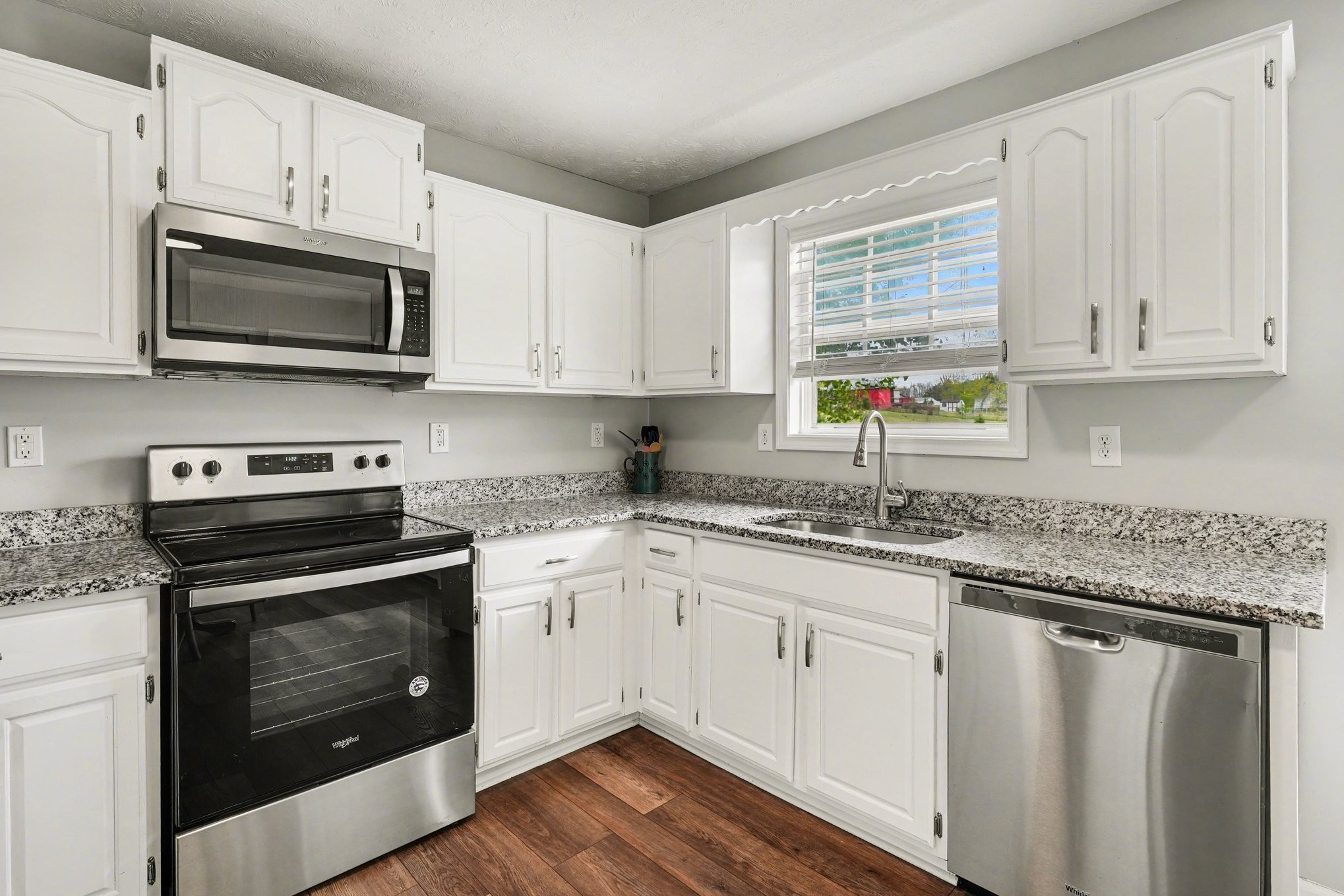 550 Gregory Road Westmoreland, TN 37186 - Photo 6 of 26 a kitchen with stainless steel appliances granite countertop white cabinets a sink a stove a microwave and a window