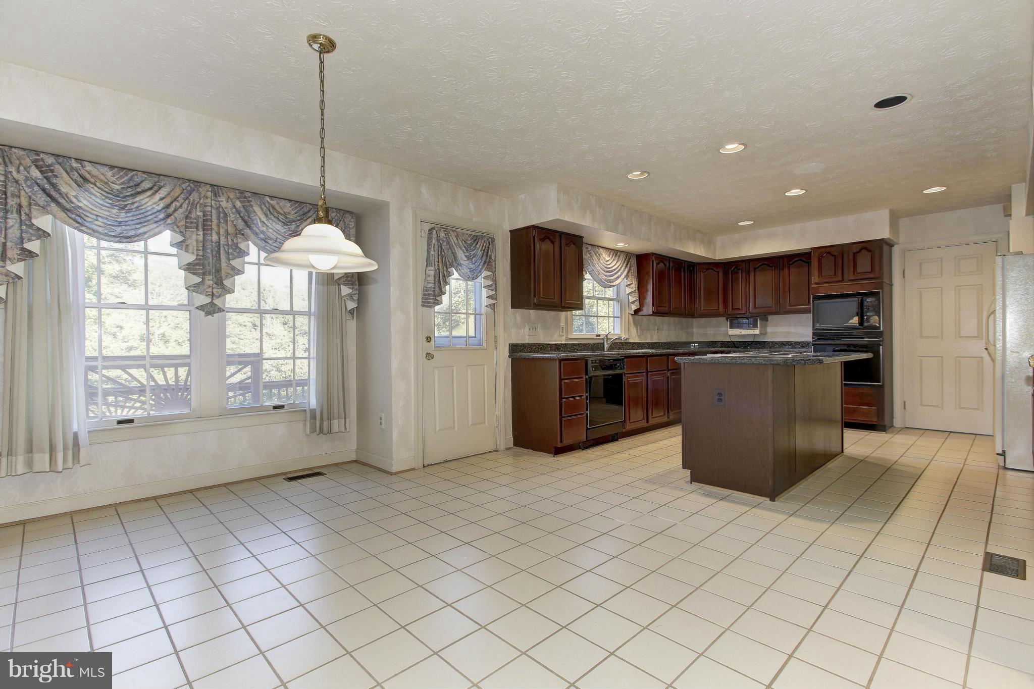 8837 Herons Flight Laurel, MD 20723 - Photo 7 of 29 a kitchen with stainless steel appliances kitchen island granite countertop a refrigerator a stove top oven and a sink with granite countertops