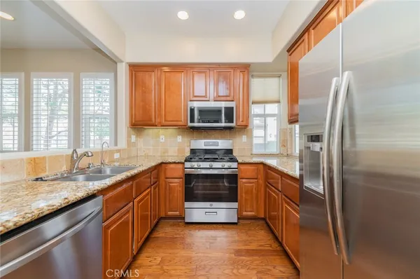 a kitchen with stainless steel appliances granite countertop a stove a sink and a refrigerator