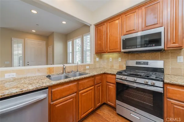 a kitchen with stainless steel appliances granite countertop white cabinets granite counter tops and a window
