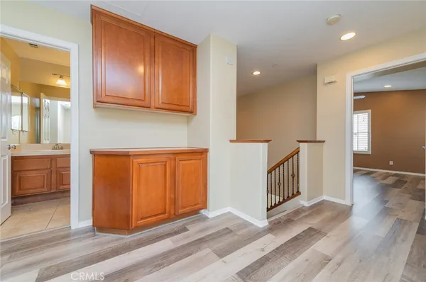 a view of a hallway with wooden floor and cabinets