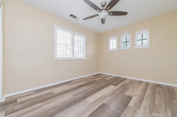 a view of empty room with wooden floor and fan