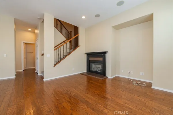 a view of an empty room with wooden floor and stairs