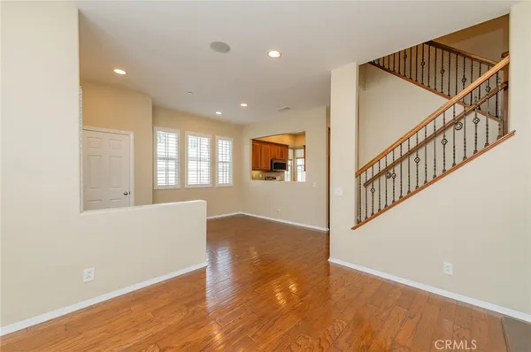 a view of an empty room with wooden floor and windows