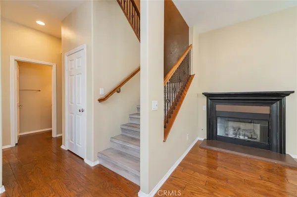 a view of an empty room with wooden floor and a fireplace