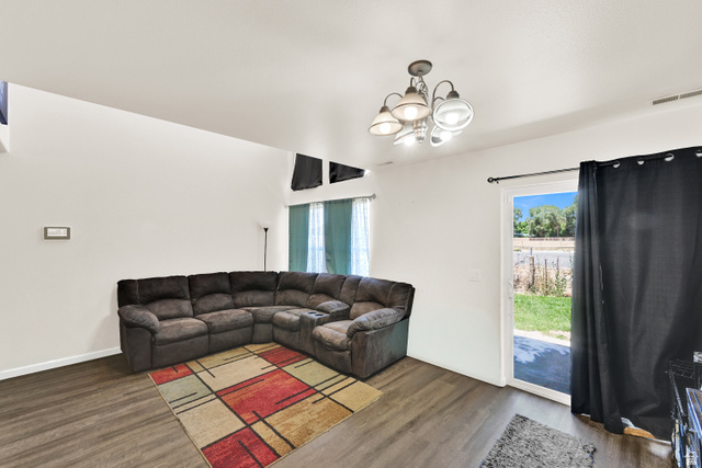 116 4th Street South Ogden, UT 84404 - Photo 2 of 7 Spacious living area featuring wood-finish flooring, a contemporary ceiling light fixture, and a sliding glass door providing exterior access