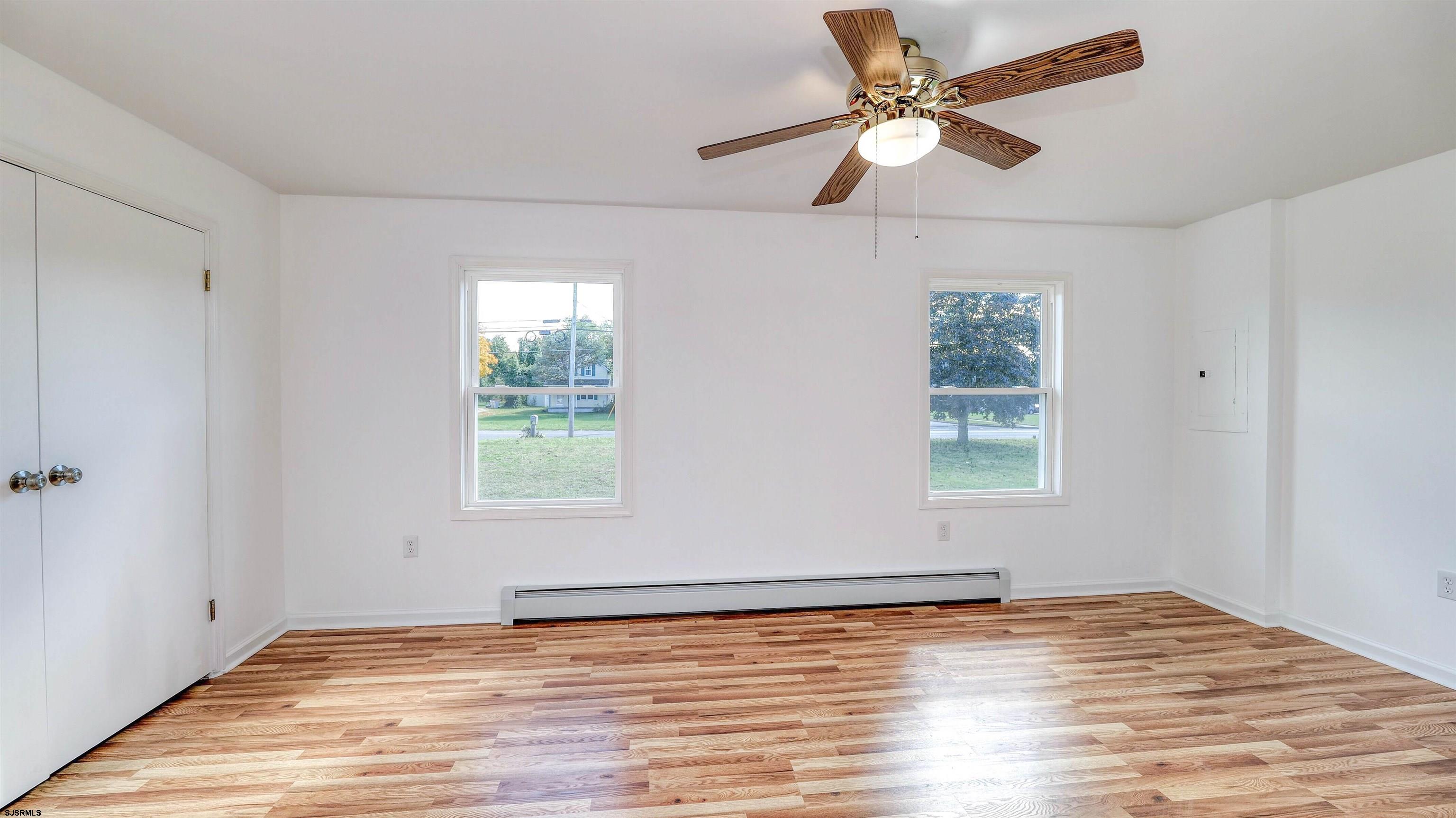 1510 East Wheat Road Vineland, NJ 08360 - Photo 16 of 26 an empty room with wooden floor chandelier fan and windows