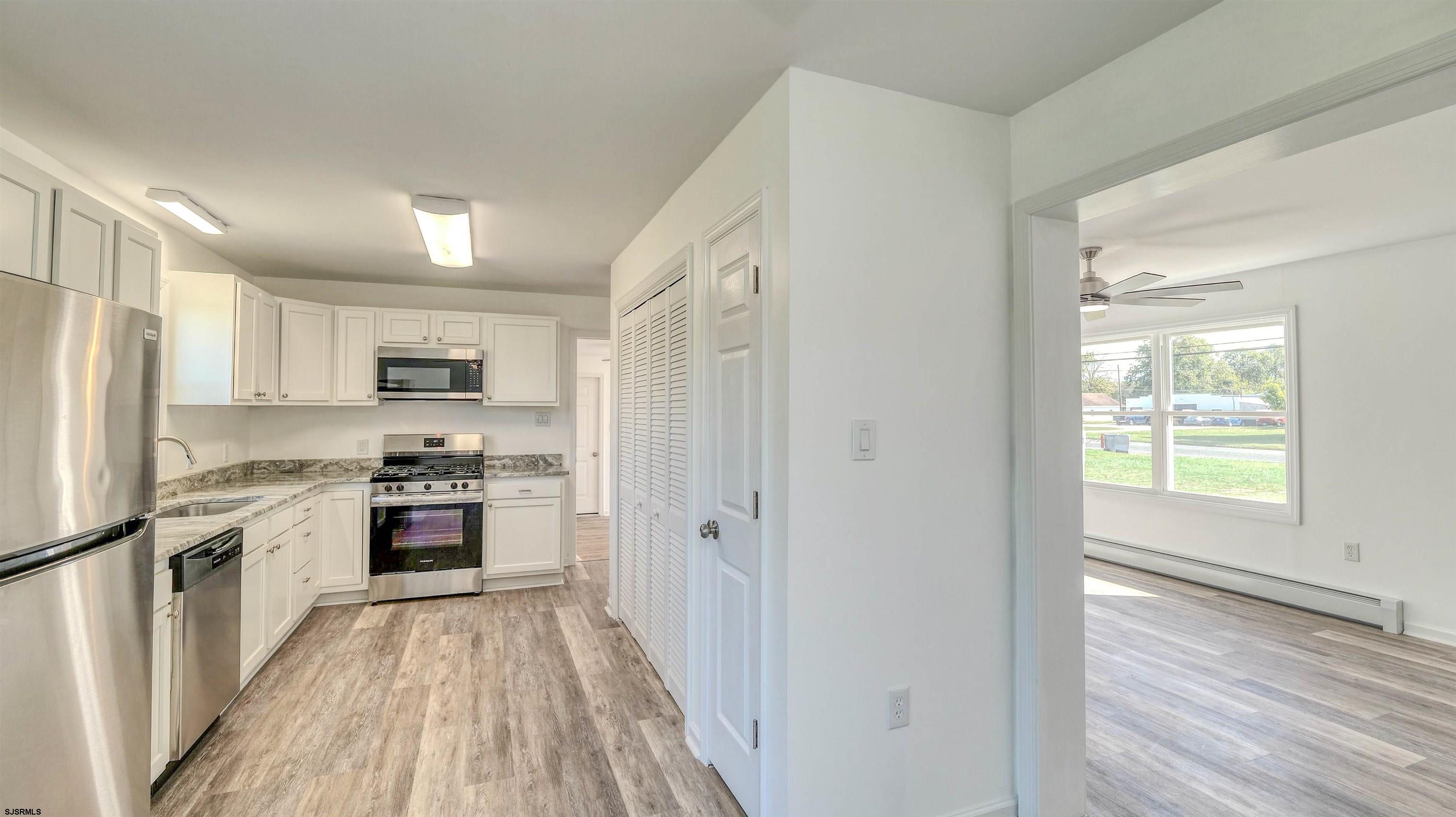 1510 East Wheat Road Vineland, NJ 08360 - Photo 9 of 26 a kitchen with stainless steel appliances granite countertop a refrigerator a stove top oven a sink and dishwasher with wooden floor