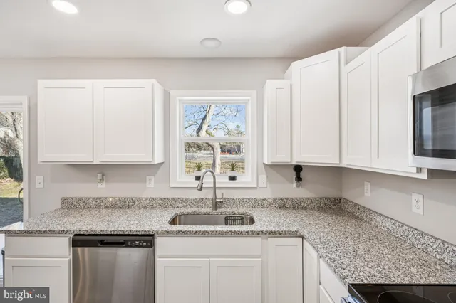 a kitchen with granite countertop a sink stainless steel appliances and cabinets