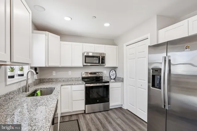 a kitchen with stainless steel appliances granite countertop a refrigerator a stove a sink and a microwave