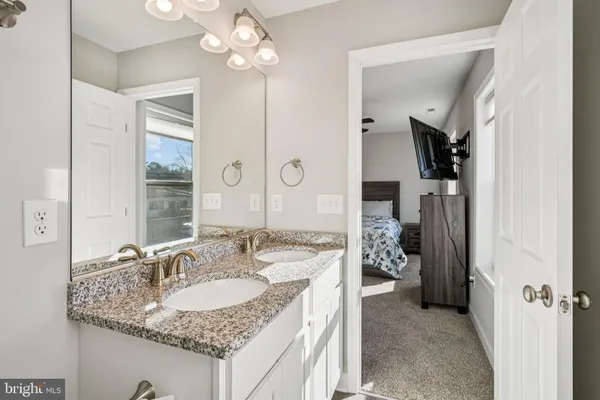 a bathroom with a granite countertop sink a light fixture and a mirror