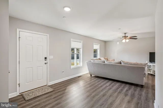 a living room with couches and kitchen view with wooden floor