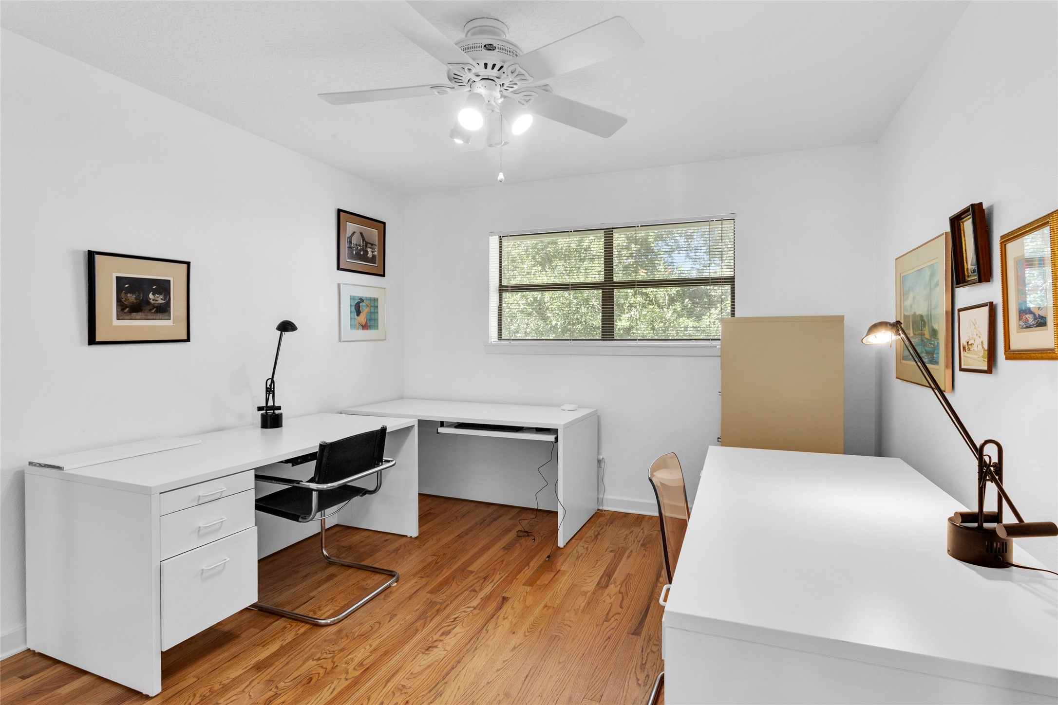 67 Harbor Lane Kemah, TX 77565 - Photo 20 of 47 This bright home office or bedroom features hardwood floors, two white desks, and ample natural light from a large window. The space is accented with modern lighting, providing a clean and productive environment.