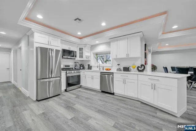 a large kitchen with white cabinets and wooden floor