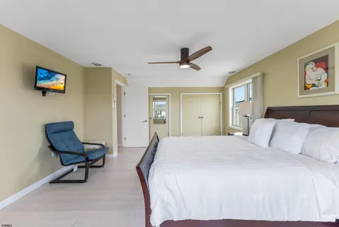 a bedroom with a bed a desk and chair with wooden floor